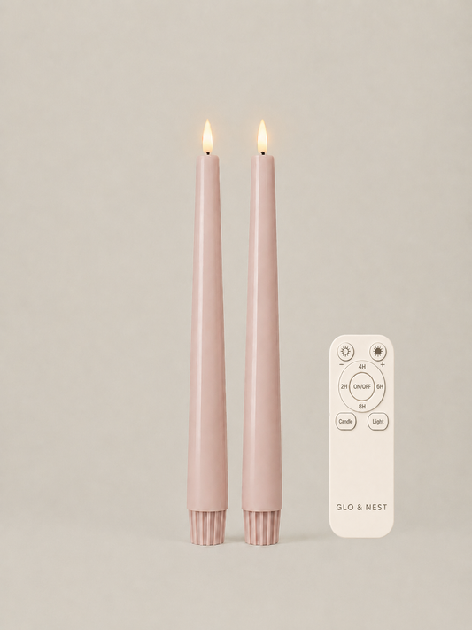 Two Powder Rose LED taper candles with the Glo & Nest remote control